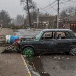 Picture of a car crashed and abandoned in a war-torn town