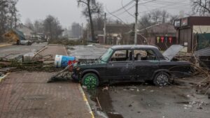 Picture of a car crashed and abandoned in a war-torn town