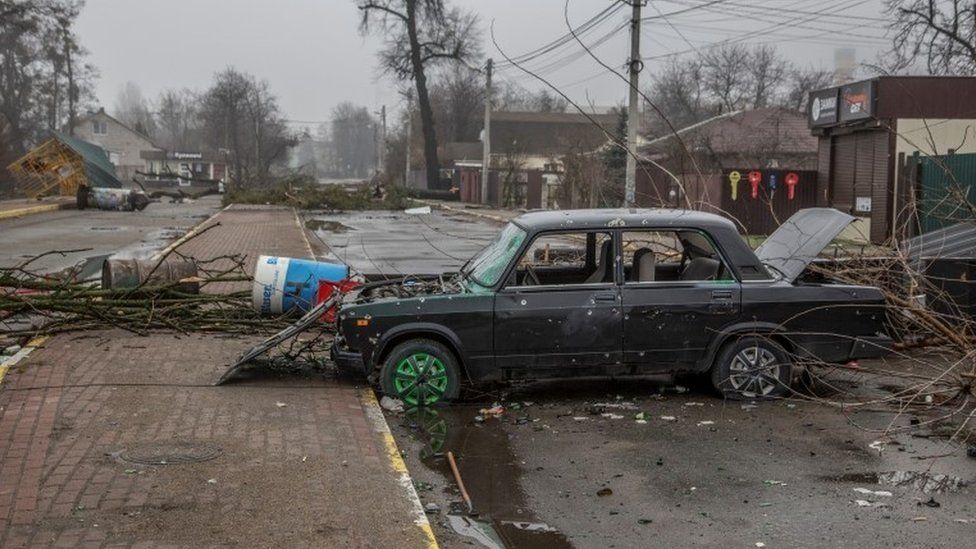 Picture of a car crashed and abandoned in a war-torn town